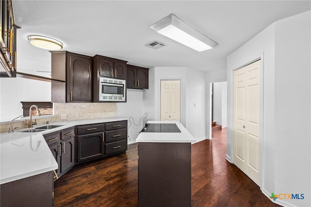 kitchen with a kitchen island, dark hardwood / wood-style floors, stainless steel microwave, sink, and dark brown cabinets