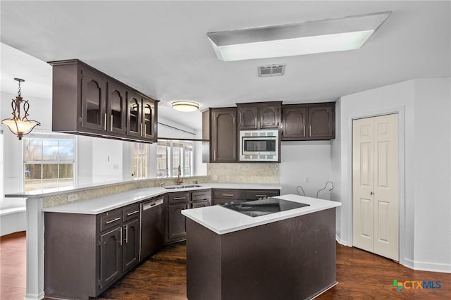 kitchen with appliances with stainless steel finishes, decorative light fixtures, sink, dark hardwood / wood-style flooring, and a center island