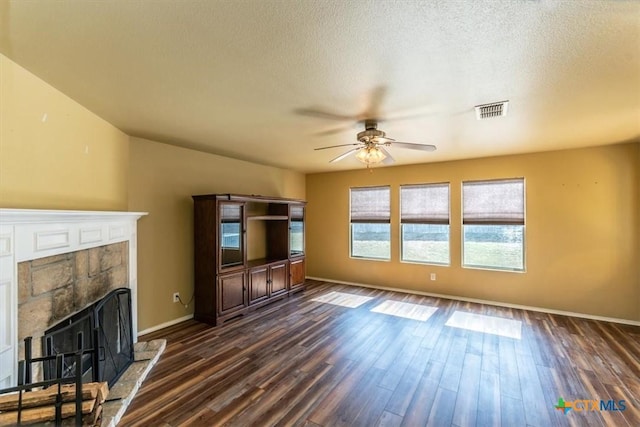 unfurnished living room featuring ceiling fan, a fireplace, dark wood-type flooring, and a textured ceiling