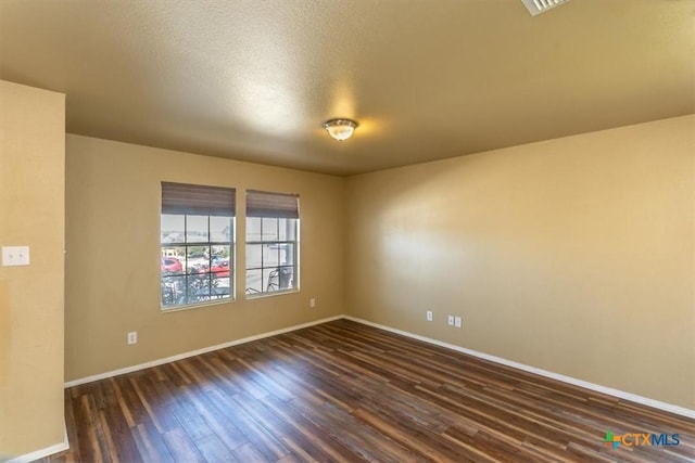 spare room featuring a textured ceiling and dark hardwood / wood-style floors