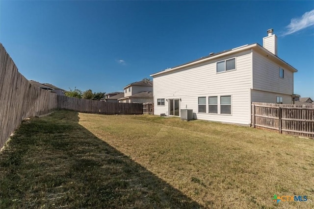 rear view of property featuring a yard and central air condition unit