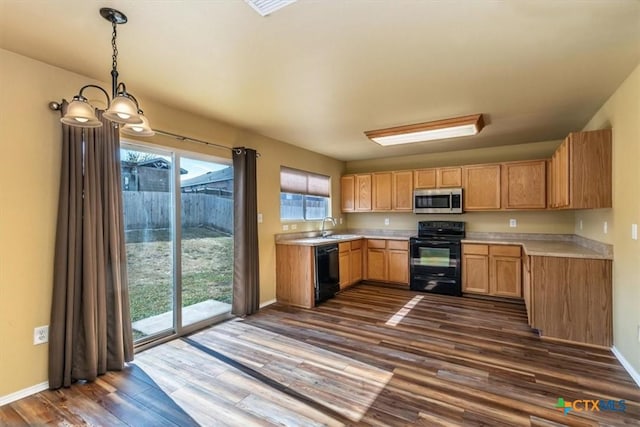 kitchen featuring dark hardwood / wood-style flooring, sink, black appliances, decorative light fixtures, and a notable chandelier