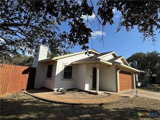 view of front facade featuring fence, a garage, and a chimney