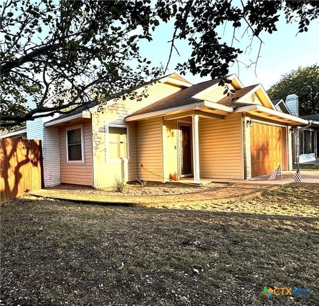 back of property with an attached garage and fence