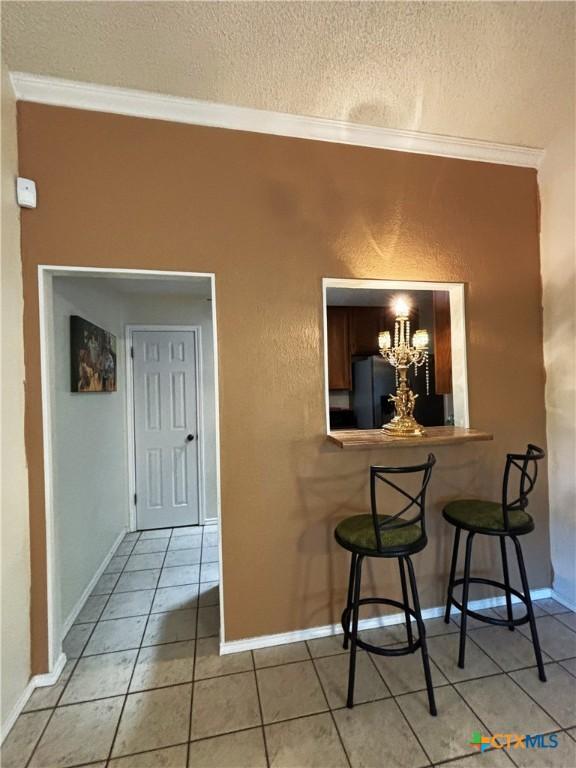 dining space featuring light tile patterned flooring, a notable chandelier, a textured ceiling, and crown molding