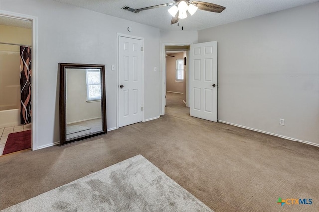 unfurnished bedroom featuring multiple windows, visible vents, carpet floors, and a textured ceiling