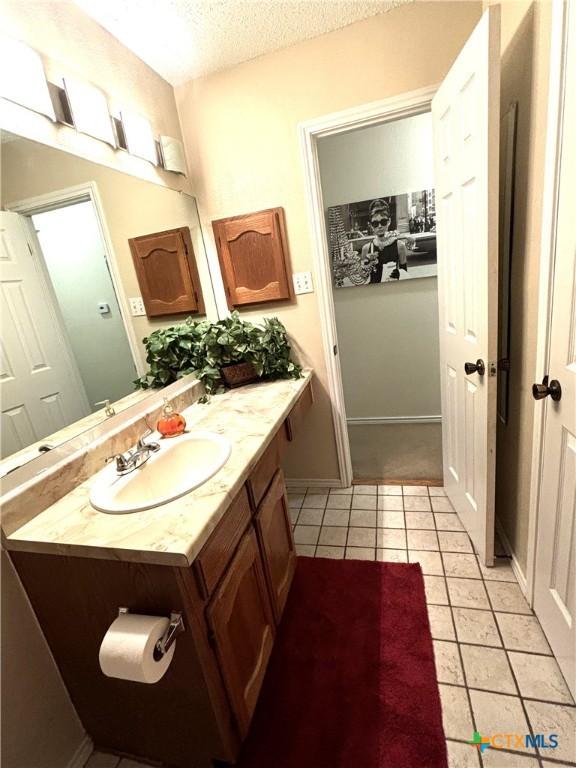 bathroom featuring tile patterned flooring, vanity, baseboards, and a textured ceiling