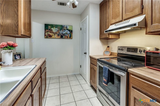 kitchen featuring visible vents, under cabinet range hood, stainless steel electric stove, light countertops, and a sink