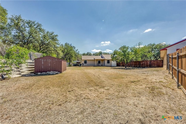 view of yard with an outbuilding, a storage unit, and fence