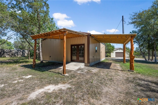 rear view of property with french doors, a garage, and an outdoor structure