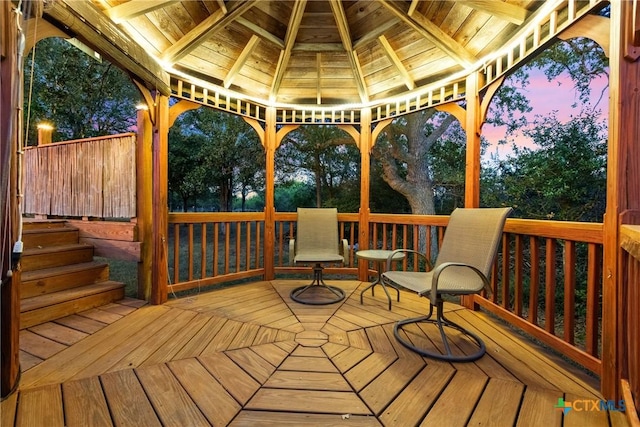 deck at dusk featuring a gazebo