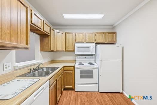 1624 Aquarena Springs Dr Unit G152, San Marcos, TX 78666 - kitchen featuring white appliances, a sink, light countertops, light wood-style floors, and ornamental molding