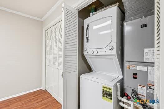 1624 Aquarena Springs Dr Unit G152, San Marcos, TX 78666 - washroom with stacked washing machine and dryer, crown molding, wood finished floors, and baseboards