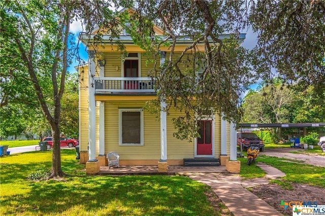 view of front of house with a balcony, a carport, and a front lawn