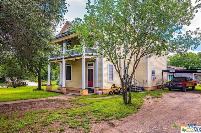 view of front of home with a balcony and a front lawn