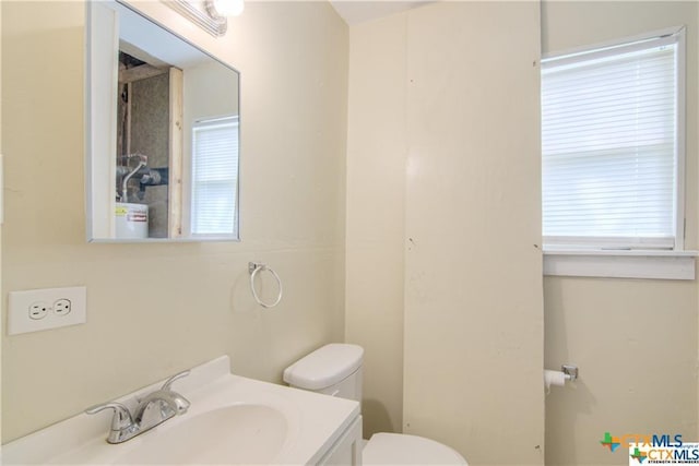 bathroom featuring toilet, vanity, and plenty of natural light