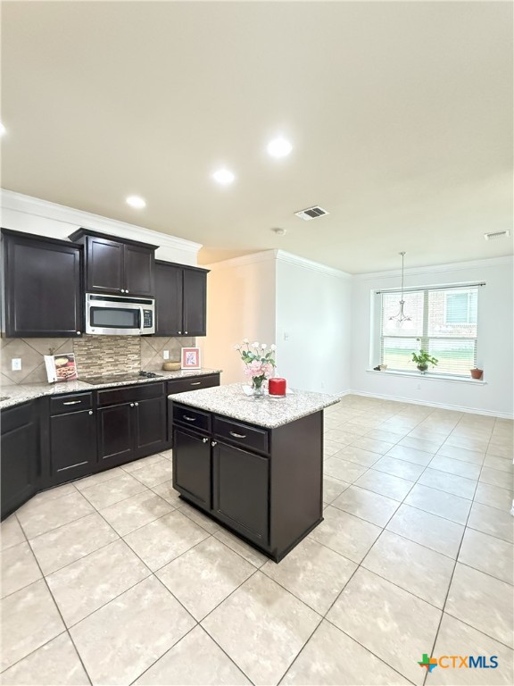 3312 Vineyard Trl, Harker Heights, TX 76548 - kitchen featuring stainless steel microwave, crown molding, dark cabinetry, tasteful backsplash, and light tile patterned floors