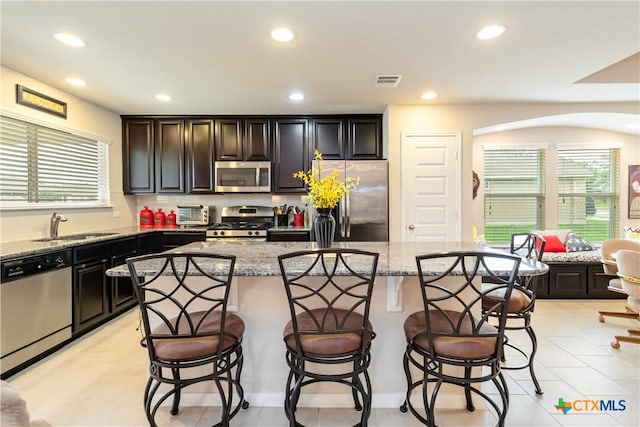 kitchen featuring a sink, a kitchen breakfast bar, stainless steel appliances, and recessed lighting