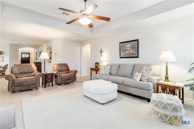 living room with light tile patterned flooring, arched walkways, a ceiling fan, baseboards, and visible vents