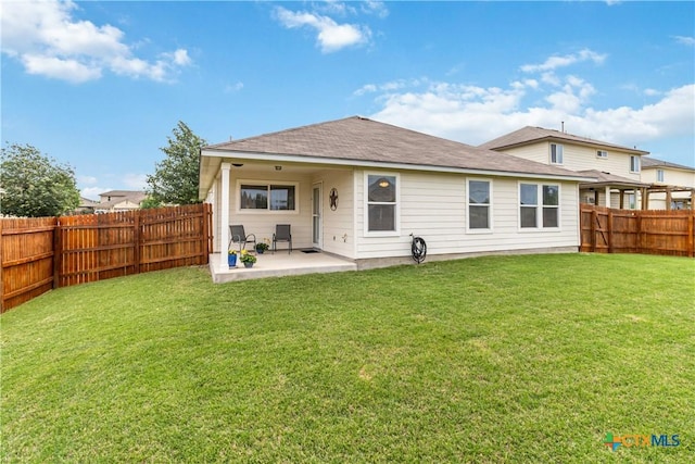 back of house featuring a fenced backyard, a patio, a shingled roof, and a yard