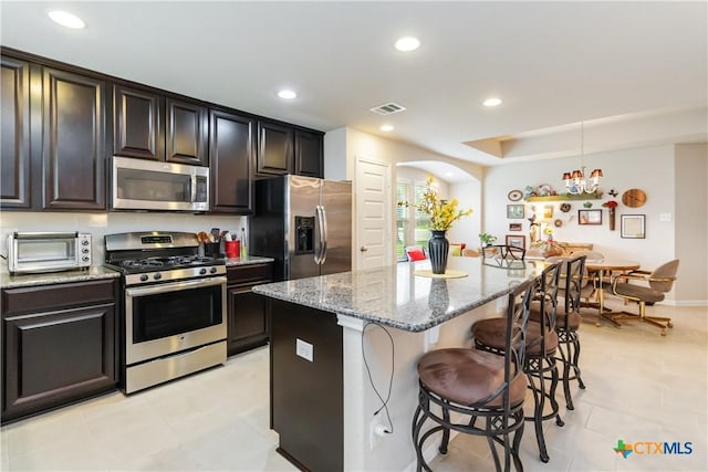 kitchen featuring light stone countertops, appliances with stainless steel finishes, a breakfast bar, a toaster, and visible vents