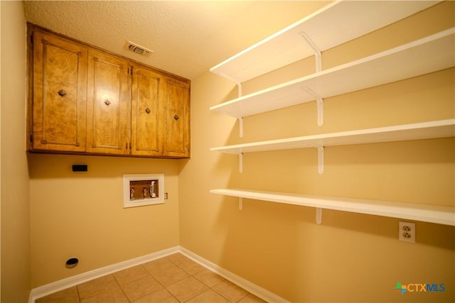 washroom featuring light tile patterned floors, hookup for a washing machine, cabinets, and a textured ceiling