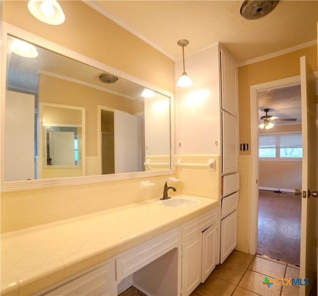 bathroom featuring tile patterned flooring, crown molding, vanity, and a textured ceiling