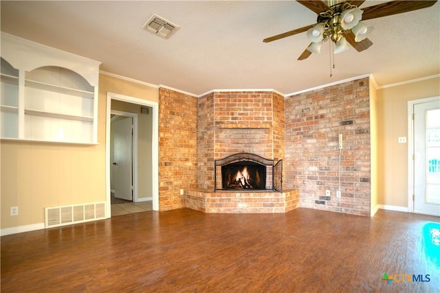 unfurnished living room featuring ceiling fan, hardwood / wood-style floors, a fireplace, ornamental molding, and brick wall