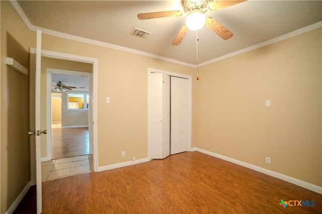 unfurnished bedroom with crown molding, light hardwood / wood-style floors, a closet, and a textured ceiling