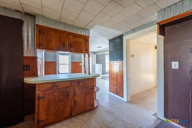 210 S Monterey St, Smiley, TX 78159 - kitchen featuring light countertops, light floors, a peninsula, and brown cabinetry