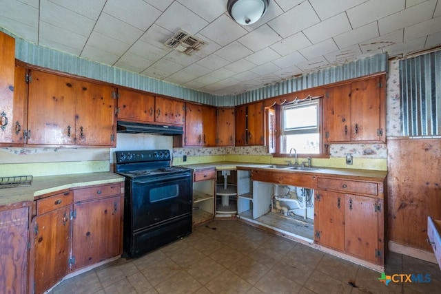 210 S Monterey St, Smiley, TX 78159 - kitchen with electric range, under cabinet range hood, brown cabinetry, tile patterned floors, and light countertops