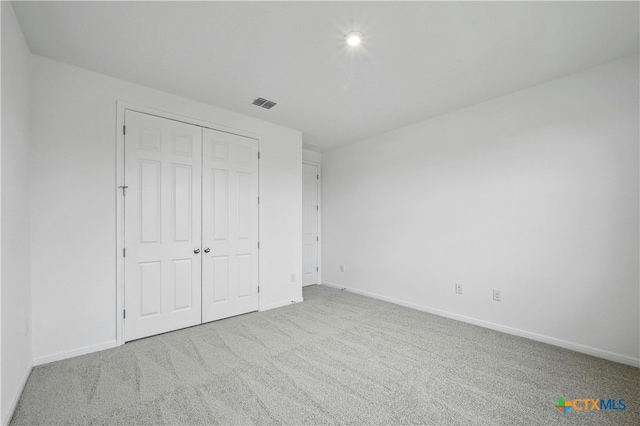 unfurnished bedroom with light carpet and a closet