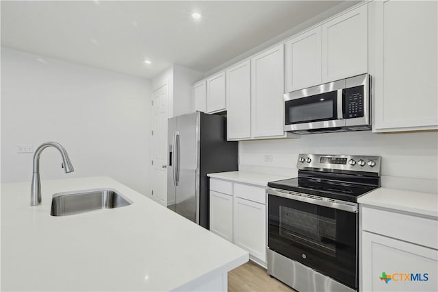 kitchen featuring light wood-type flooring, stainless steel appliances, white cabinetry, and sink