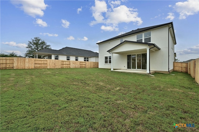 back of house with a yard and a patio