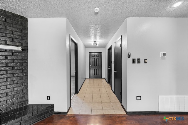 hall featuring a textured ceiling and light tile patterned floors