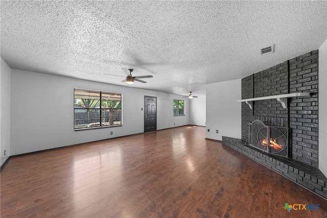 unfurnished living room with hardwood / wood-style floors, a fireplace, a textured ceiling, and ceiling fan