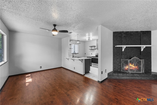 unfurnished living room featuring a brick fireplace, wood-type flooring, and a textured ceiling