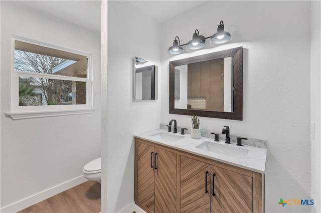 full bathroom with toilet, wood finished floors, baseboards, and a sink