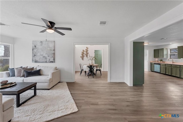 living room featuring visible vents, baseboards, a textured ceiling, and wood finished floors