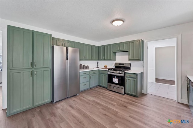 kitchen with green cabinetry, light wood-style floors, appliances with stainless steel finishes, and light countertops