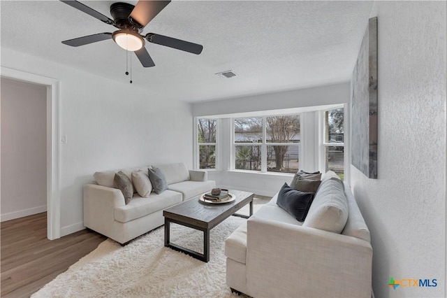 living room with visible vents, a textured ceiling, a healthy amount of sunlight, and wood finished floors