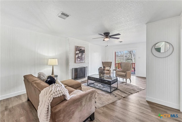 living area featuring visible vents, a textured ceiling, wood finished floors, and a fireplace