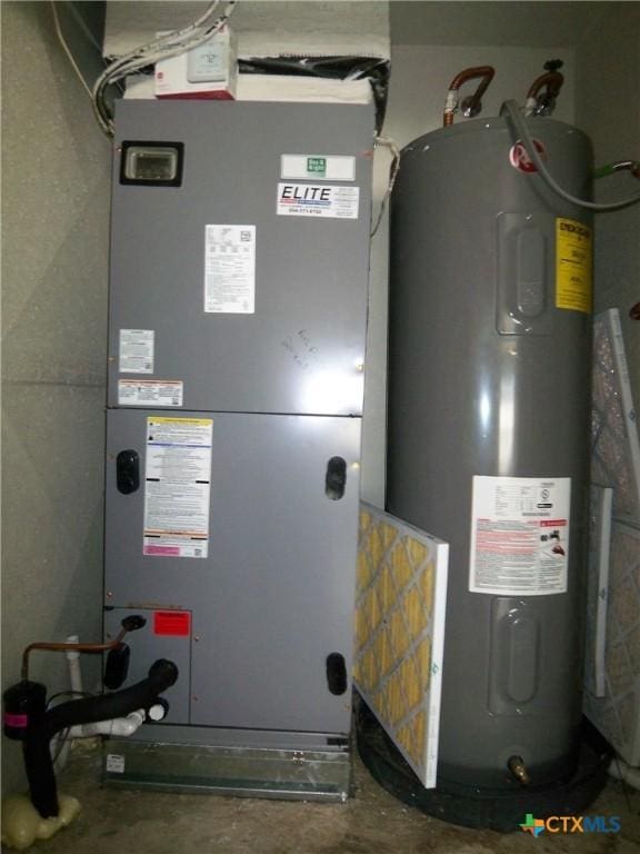 utility room featuring heating unit and electric water heater