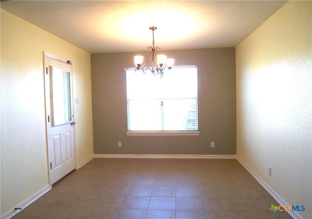 tiled spare room with a notable chandelier