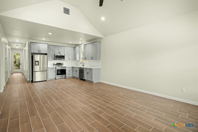 kitchen with stainless steel appliances, gray cabinets, high vaulted ceiling, sink, and light hardwood / wood-style floors