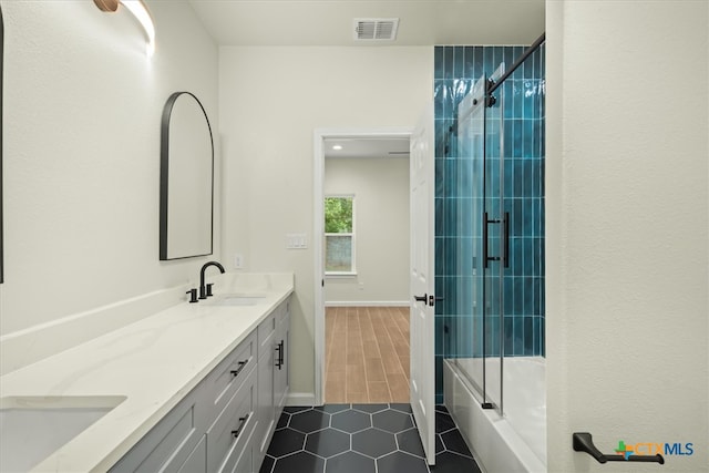 bathroom featuring hardwood / wood-style floors, vanity, and bath / shower combo with glass door