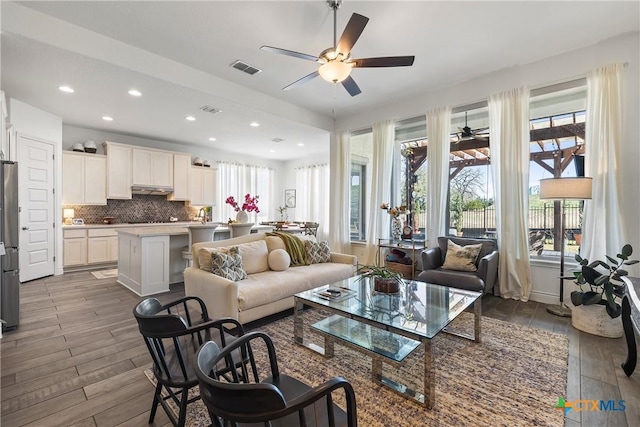 living room featuring hardwood / wood-style flooring, plenty of natural light, and ceiling fan