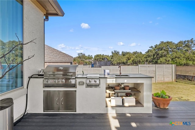 wooden deck featuring area for grilling, sink, and an outdoor kitchen