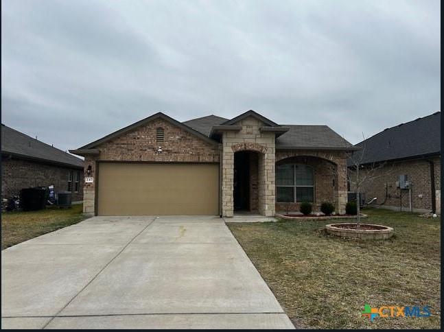 view of front of home featuring a garage, central AC unit, and a front lawn