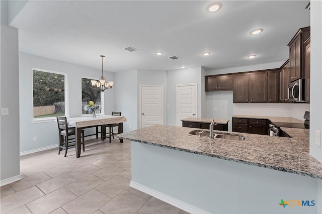 kitchen with dark brown cabinetry, a sink, visible vents, appliances with stainless steel finishes, and light stone countertops